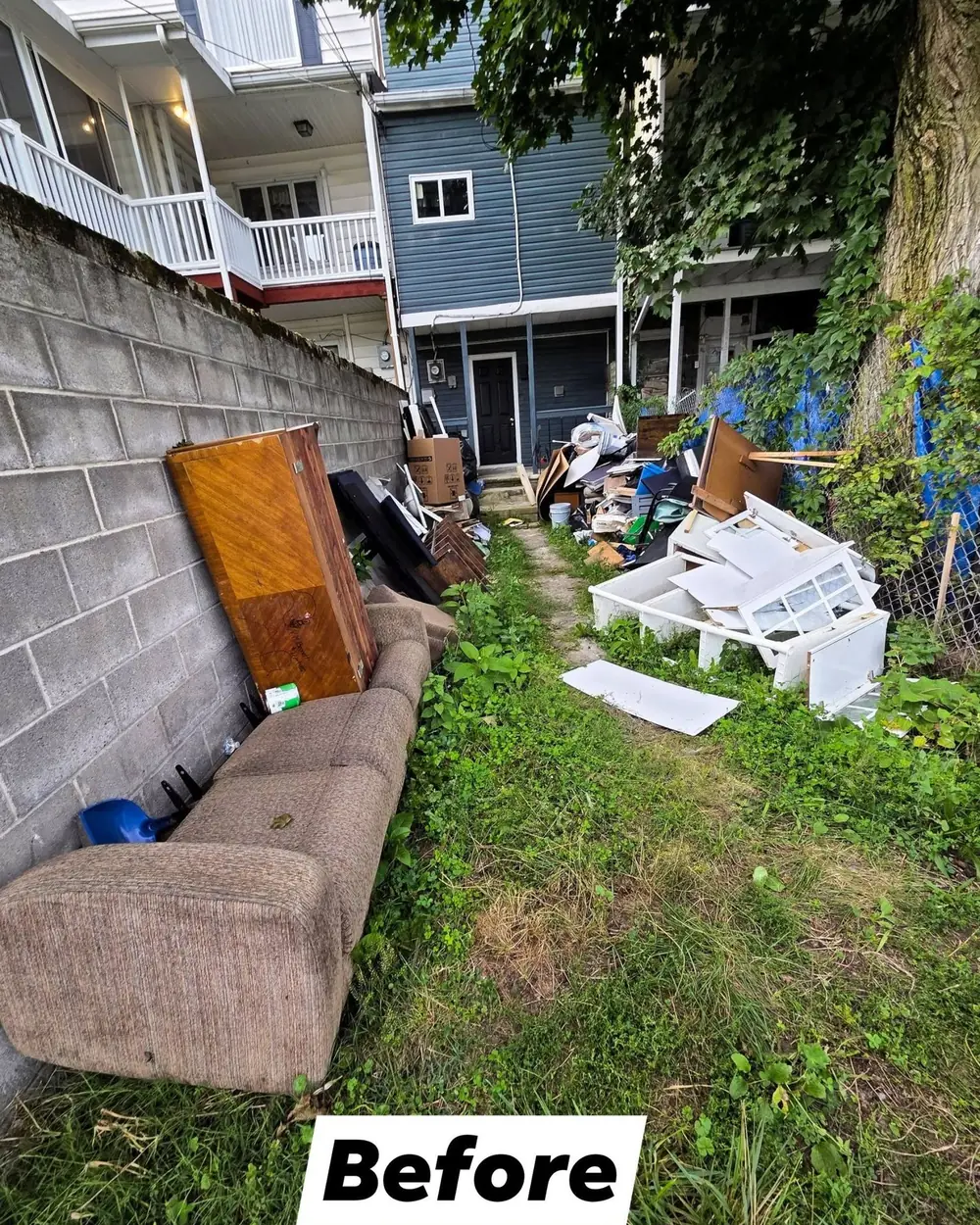A back yard behind a Shenandoah rowhouse filled with a sofa, cabinets and household junk
